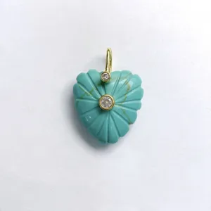 Detailed close-up view of carved turquoise heart pendant with gold bail and crystal stones.