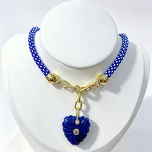 Blue braided rope necklace with carved blue heart pendant and gold metal details detail view.