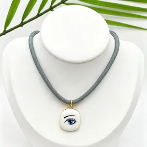Chic grey cord necklace with gold-trimmed white enamel blue eye pendant for fashion women.