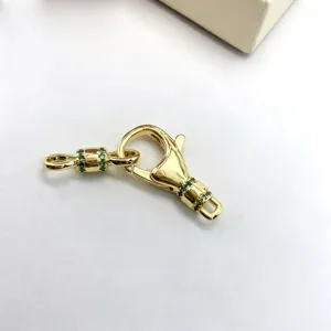 Close-up detail of gold-plated brass DIY jewelry clasp connector with green micro pave stones.
