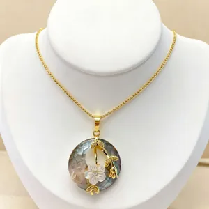 Details of the delicate gold clavicle chain with natural mother-of-pearl pendant and floral decor.