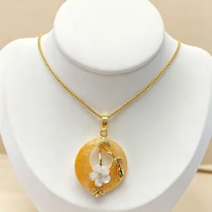 Close-up of shell flower pendant necklace featuring gold chain and vintage aesthetic design details.