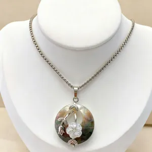 Detail view of the natural abalone shell pendant necklace with floral accent and silver chain.