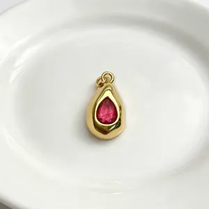 Elegant teardrop gold pendant with vibrant red gemstone, minimalist fashion juwelry accessory.