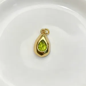 Close up detail of the teardrop green gemstone pendant, featuring a polished gold finish.