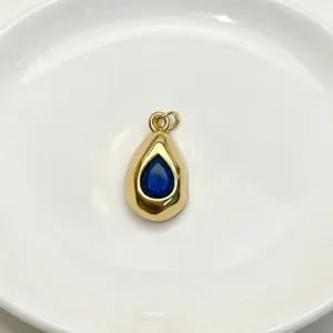 Gold teardrop pendant with blue gemstone detail shot, elegant fashion jewelry accessory.