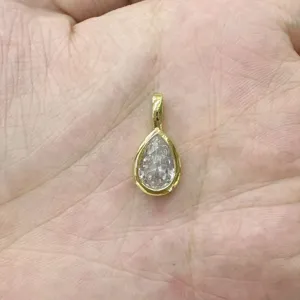 Primo piano dettaglio di un ciondolo in zircone taglio a pera dorato per accessori di gioielleria.