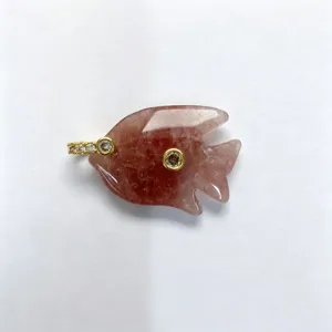 Close-up detail of carved crystal fish pendant with sparkling zirconia and gold metal trim.