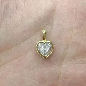Primo piano dettagliato di un ciondolo a cuore placcato in oro con zircone cubico brillante.