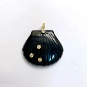 Nahaufnahme des schwarzen, geschnitzten Muschelanhängers mit funkelnden Zirkonias und Golddetails.