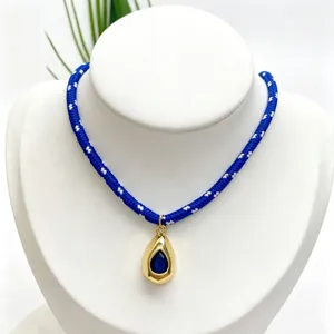 Blue and white braided rope necklace with gold teardrop blue gemstone pendant detail view.