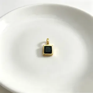 Nahaufnahme eines minimalistischen vergoldeten quadratischen Anhängers mit schwarzem Zirkon.