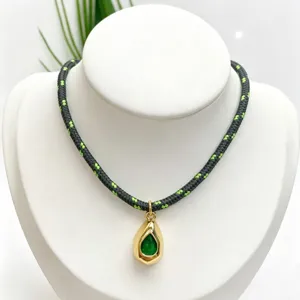 Close-up detail of the stylish woven rope necklace featuring a gold teardrop green gemstone pendant.