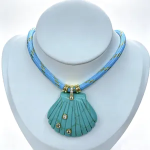 Detailansicht einer blau geschnitzten Muschel-Halskette mit funkelnden Zirkonen und Seilkette.
