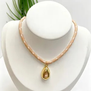 Close-up of gold drop gemstone pendant with beige braided rope chain on display bust.