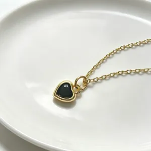 Exquisite vergoldete Halskette mit schickem schwarzen Herz-Zirkon-Anhänger, Detailaufnahme.