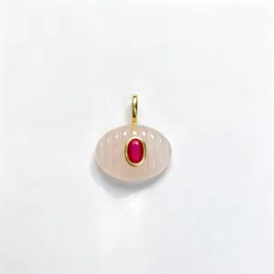 Primo piano dettagliato di pendente in pietra rosa ovale scanalata con gemma rossa e anello.