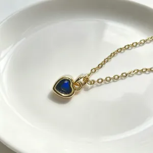 Nahaufnahme einer vergoldeten blauen Zirkon Herz Anhänger Halskette mit feinem Schmuckdetail.