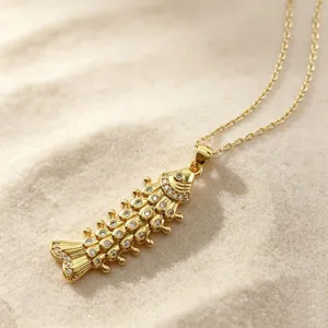 Detailed view of the sparkling micro-pave cubic zirconia articulated fish pendant necklace on sand.