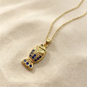 Gold fish pendant necklace inlaid with sparkling blue cubic zirconia stones for women.