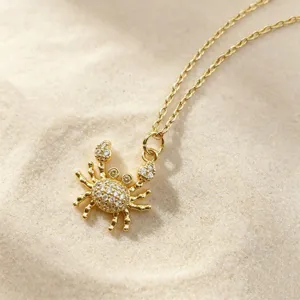 Detailed shot of a delicate gold-toned crab pendant necklace sparkle with cubic zirconia.