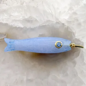 Dettaglio pendente pesce in pietra blu, gemma intarsiata oro, sfondo in cristallo.