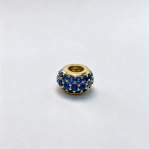 Close-up detail of a gold plated DIY charm bead with sparkling blue cubic zirconia stones.