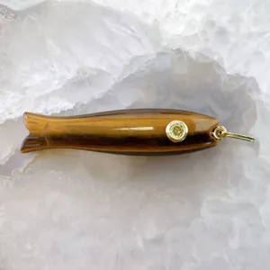 Primo piano dettagliato di un ciondolo pesce in pietra occhio di tigre con occhiello metallo.