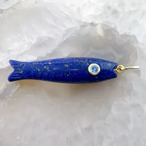 Dettaglio macro del ciondolo a forma di pesce in lapislazzuli con dettagli dorati.