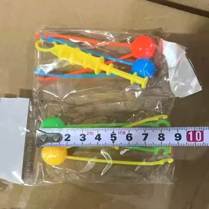Detailed view of colorful plastic swinging toys in transparent bags with size tape.