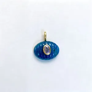 Primo piano del ciondolo ovale in pietra blu scolpita con zircone viola centrale e gancio dorato.