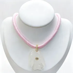 Detailed view of carved crystal tropical fish pendant with zircon and pink cord necklace.