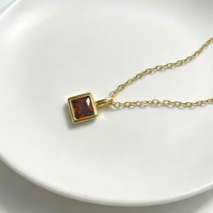 Nahaufnahme Detail einer goldenen quadratischen roten Zirkonia Anhänger Halskette, edler Schmuck.