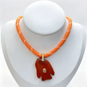 Detailed view of a unique gemstone carved fish pendant necklace with sparkling zircon accents.