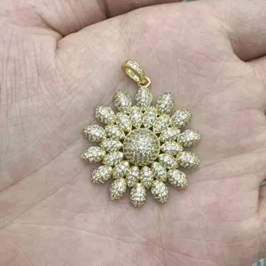 Gold flower pendant detail view, showing intricate pave rhinestone petals and sparkling center.