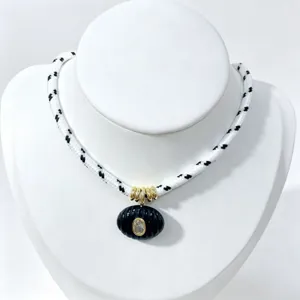 Elegante collana in stile vintage con ciondolo nero scanalato e dettagli a catena dorata.