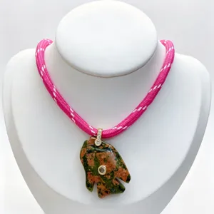 Detailed close-up of the carved stone fish pendant with sparkling diamond accents and pink cord.