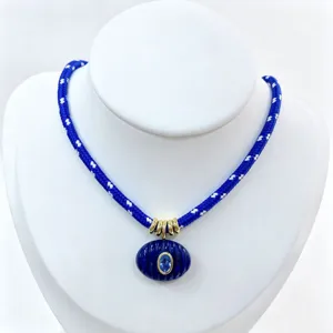 Vista dettagliata della collana in corda blu con ciondolo ovale scanalato e pietra, accessorio.