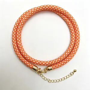 Orange and white braided rope necklace detail showcasing the intricate woven pattern and gold clasp.