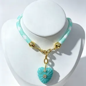 Turquoise carved heart pendant necklace with woven cord and gold-plated hardware details.