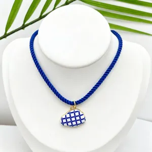 Blue rope cord necklace featuring blue and white grid ceramic cloud pendant detail.