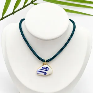 Detail view of gold-plated enamel white cloud pendant necklace with dark green rope chain.