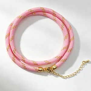 Detail view of pink braided cord necklace with metallic gold accents and extension chain.