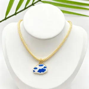 Close-up detail of the gold-toned twisted chain necklace featuring a blue and white cloud pendant.