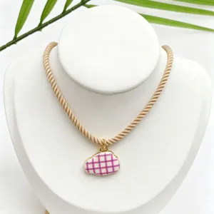 Closeup detail of cute pink grid cloud pendant necklace with beige twisted rope chain accessory.