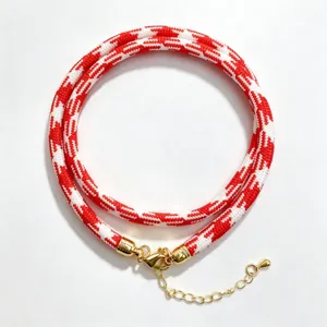 Detailed shot of the red and white houndstooth woven rope necklace with gold hardware.