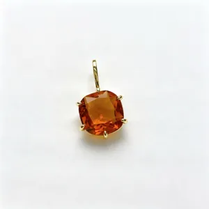 Close-up of square orange zircon pendant detail, shiny gold metal setting and stone texture.