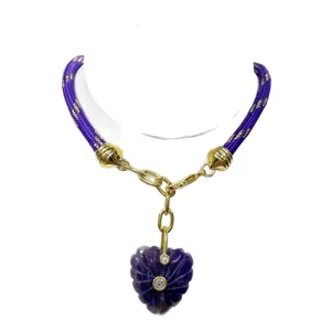Carved crystal heart pendant necklace with purple braided cord and gold-tone metal links.
