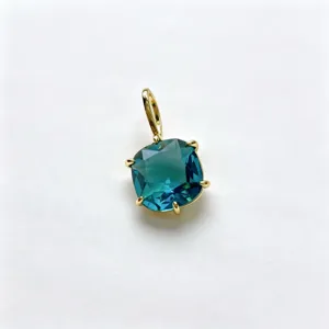 Close-up view of a cushion cut teal blue zircon pendant in a polished gold tone setting accessory.