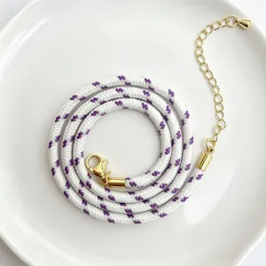Detailaufnahme der 3mm Kordel, weiß-lila geflochten mit goldenem Karabiner und Verlängerungskette.